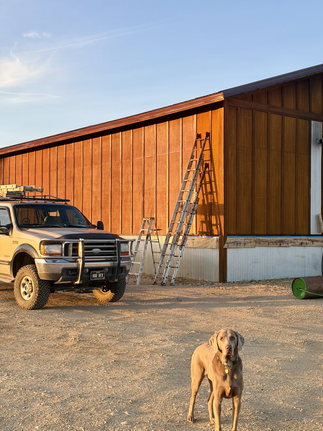 Hudson Development truck and dog at a barn staining job at sunset