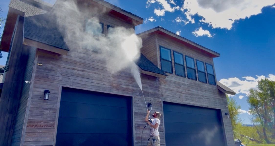 Lucien pressure washing a two-story garage in Driggs